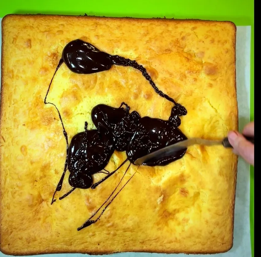 Spreading chocolate ganache over the square sheet cake.