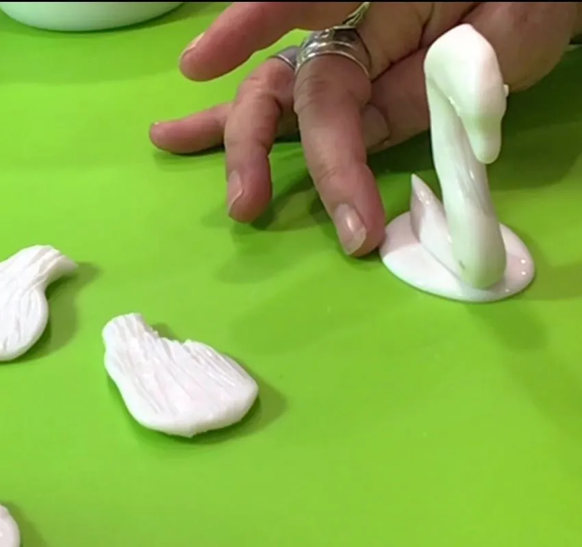 Attaching isomalt wings and tail to the swan body with warm isomalt.