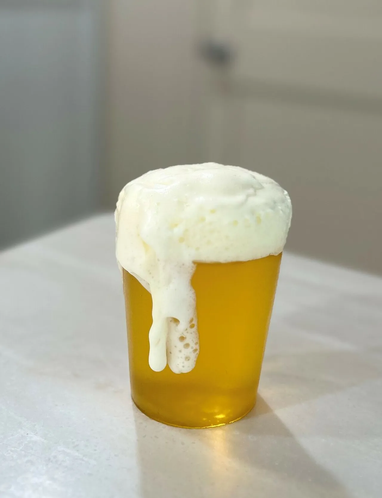 A gummy candy replica of a beer pint with golden liquid and white foam