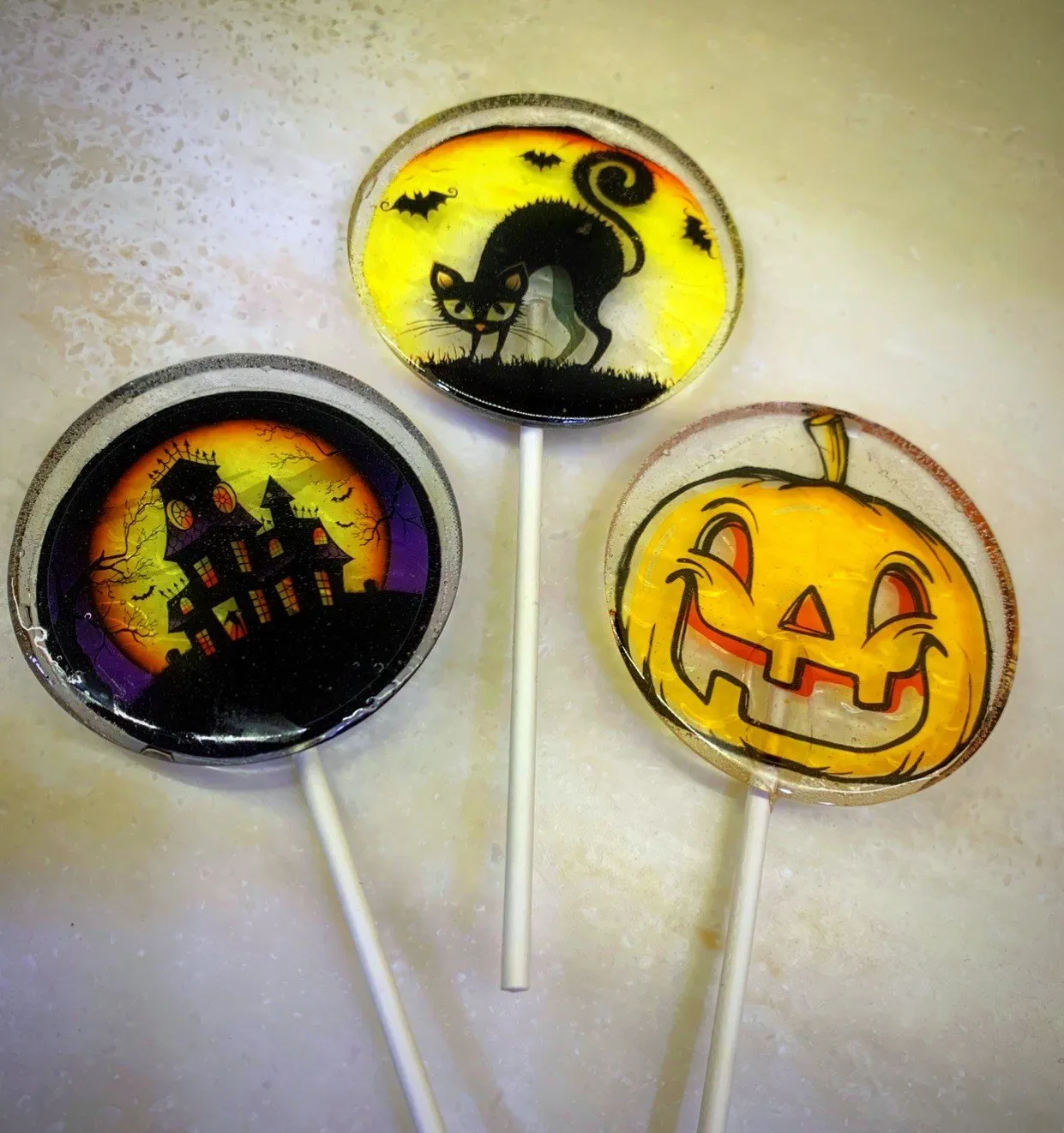 Three Halloween lollipops with haunted house, black cat, and jack-o'-lantern designs