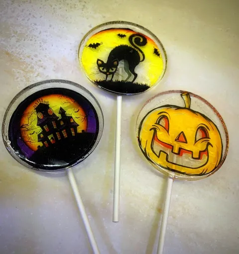 Three Halloween lollipops with haunted house, black cat, and jack-o'-lantern designs