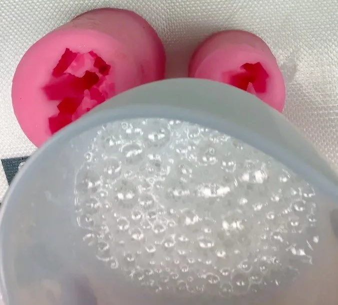 Clear isomalt bubbling in a silicone cup beside gemstone silicone molds.