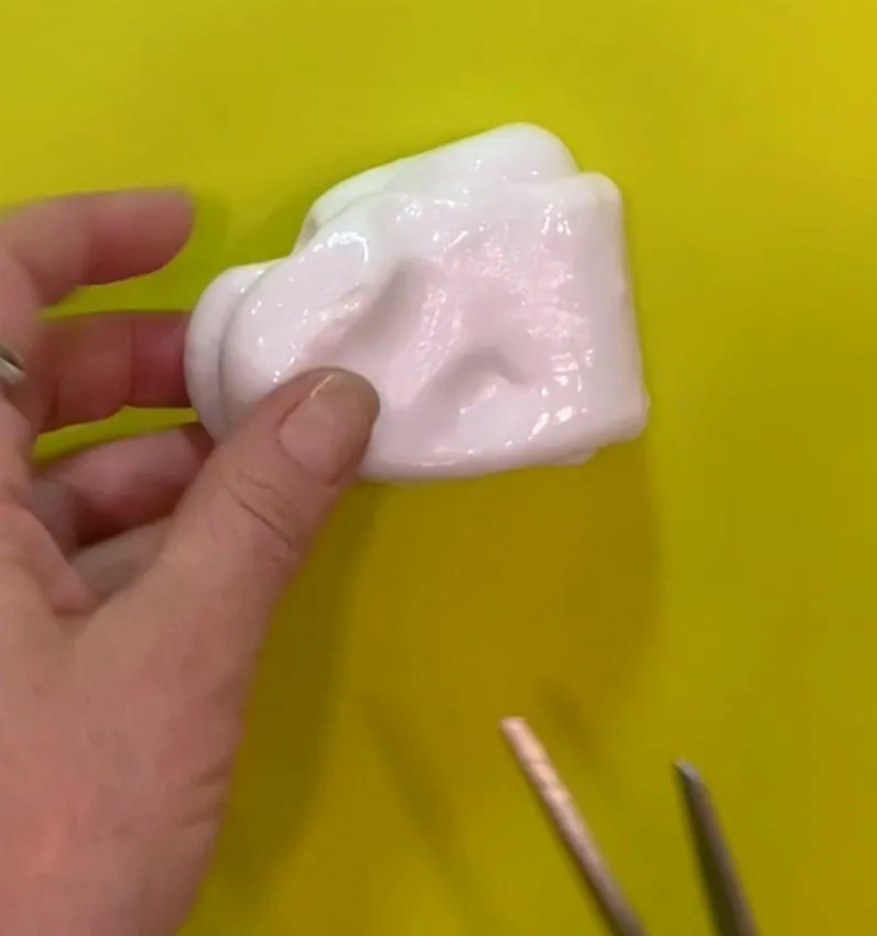 Hand holding warm, pliable isomalt being worked on a silicone mat.