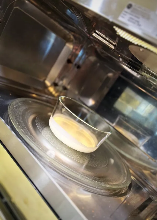 Glass bowl of cream heating in a microwave