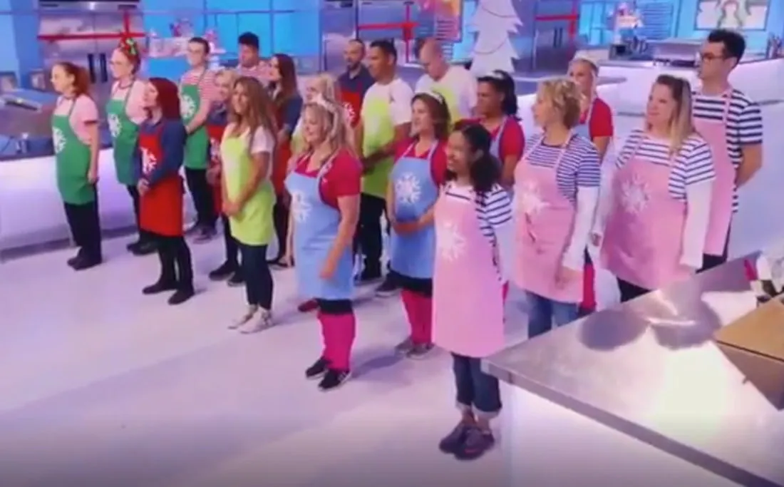 Contestants in aprons with snowflake logos on the Holiday Wars set.