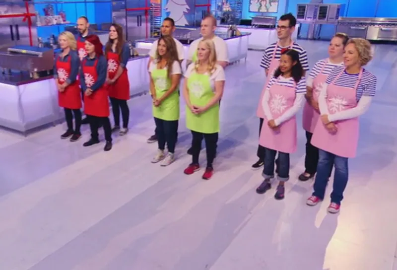Contestants in aprons standing in a television studio kitchen on Holiday Wars.