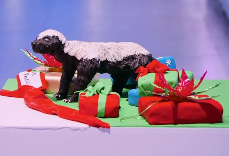 A sculpted black and white sheep cake with wrapped Christmas presents.