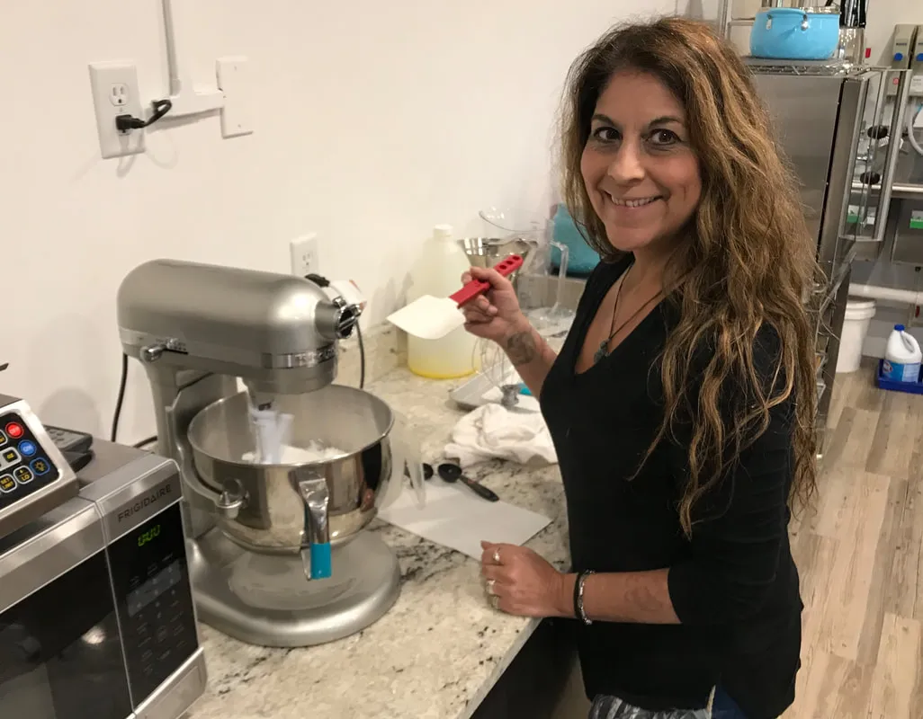Kim Simons holding a spatula in a commercial kitchen at The Sweet Chalet.