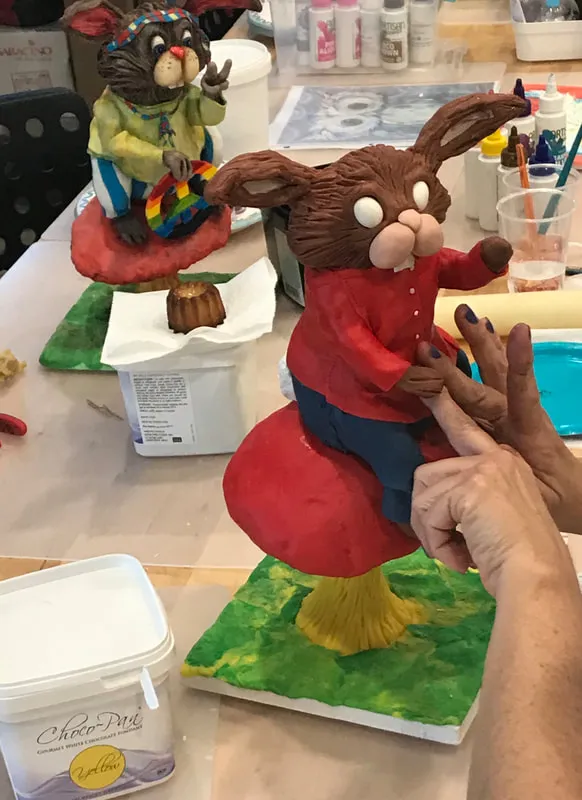 Hands adjusting a brown rabbit figurine on a mushroom at The Sweet Chalet.