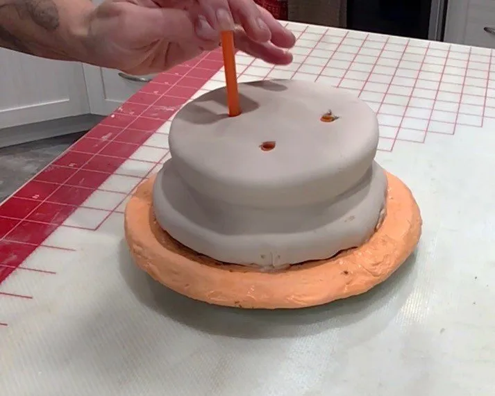 A hand inserts cake straws into the bottom bun for structural support.