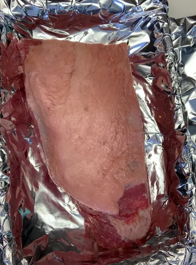 Raw brisket on a foil-lined pan