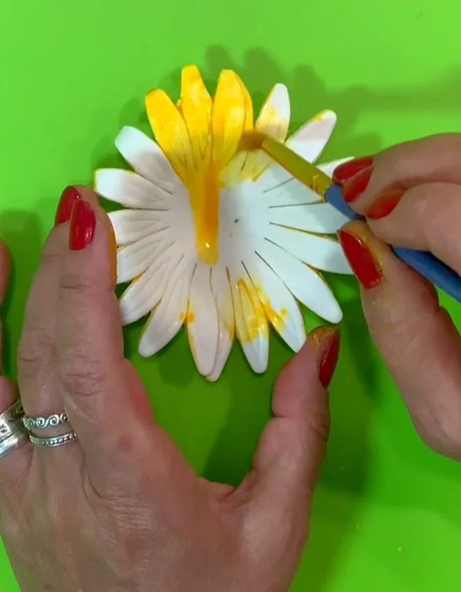 Hand painting yellow edible color onto a gumpaste sunflower.