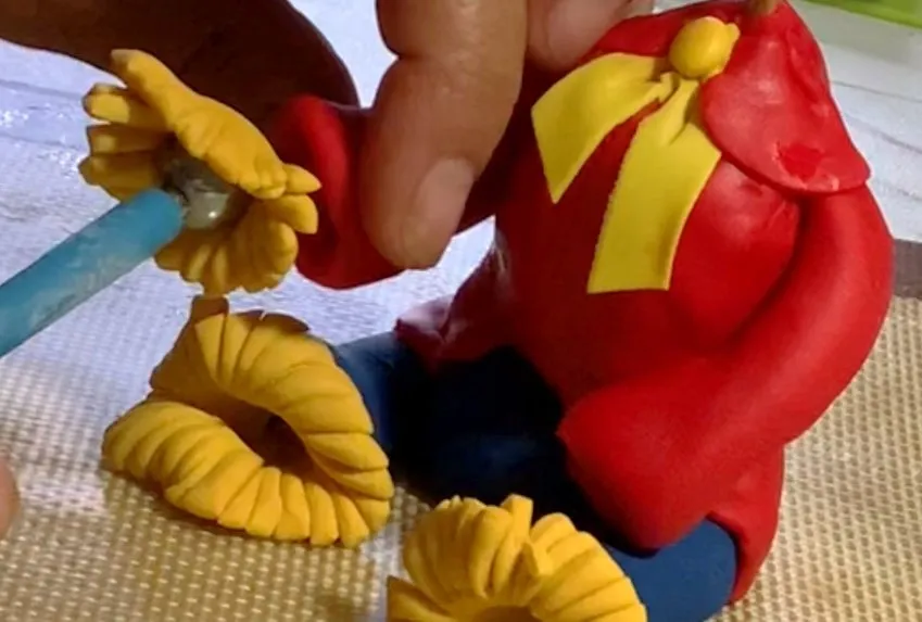 Shaping fondant arms with yellow straw at the bottom.