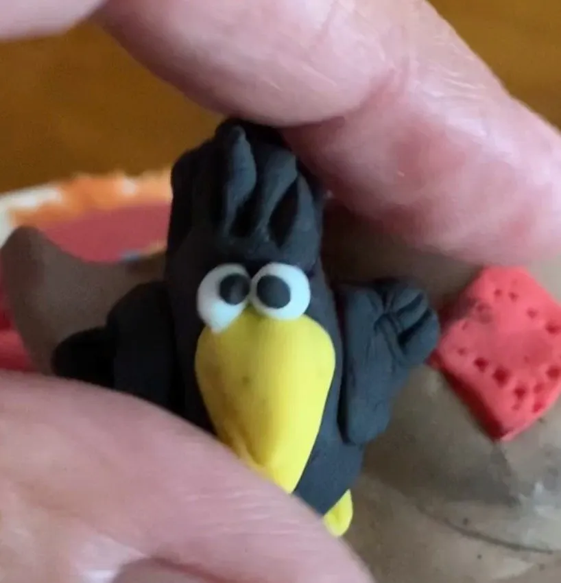 Small black fondant crow with a yellow beak on the hat.