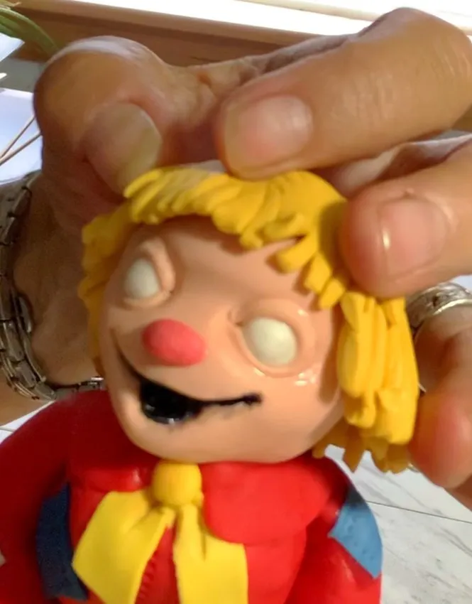 Yellow fondant straw hair with scissors placed on the head.