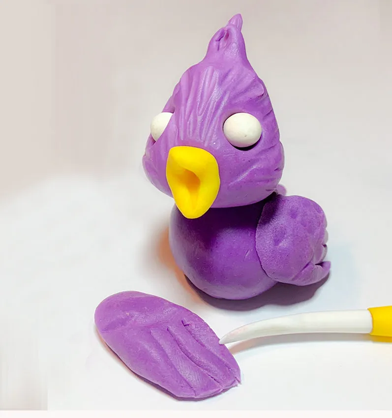 Purple modeling chocolate lovebird with wings being shaped nearby.