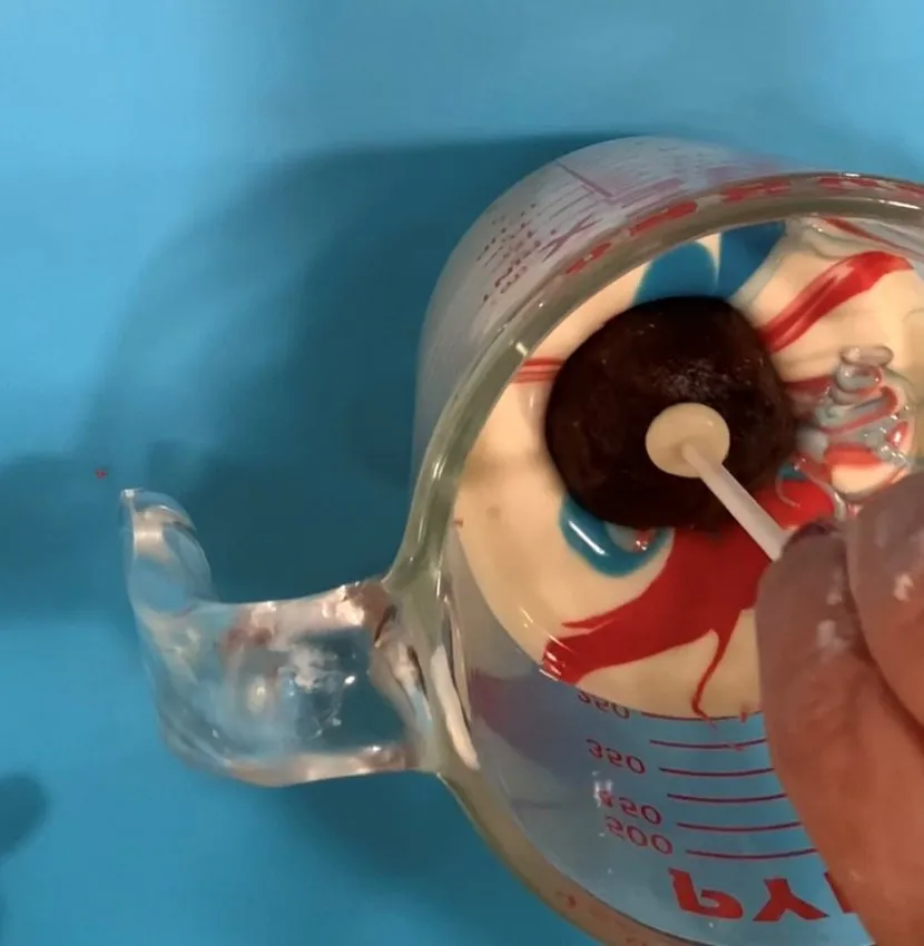 Hand dipping a cake pop into marbled red, white, and blue chocolate.