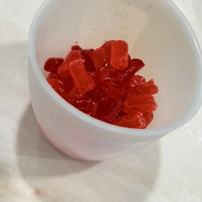 Melted red hard candy in a glass measuring cup.