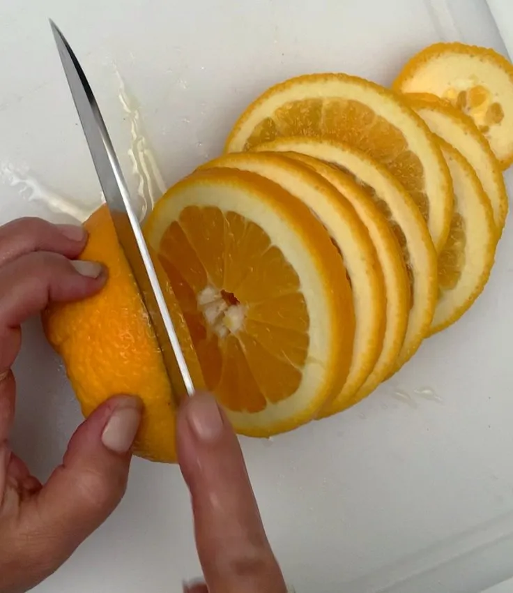 Slicing an orange into rounds on a cutting board