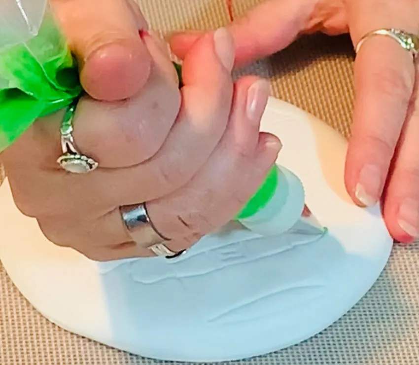 Outlining the owl design with green royal icing.