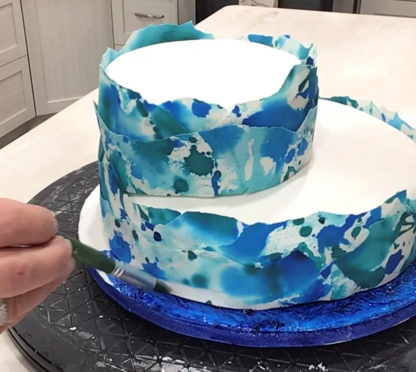 Painting the cake board blue with a brush.