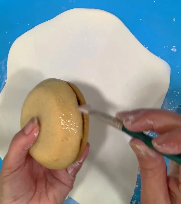 Brushing piping gel onto the cookie body.