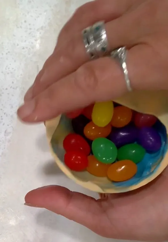 Hand holding a glass bowl filled with colorful jelly beans.