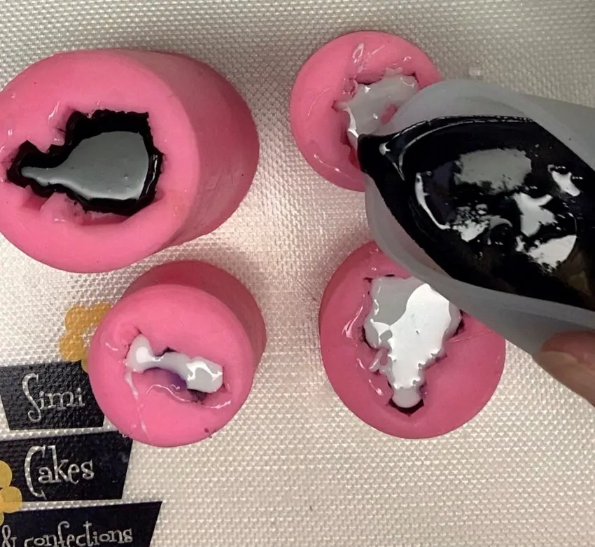 Pouring black melted isomalt into gemstone silicone molds.