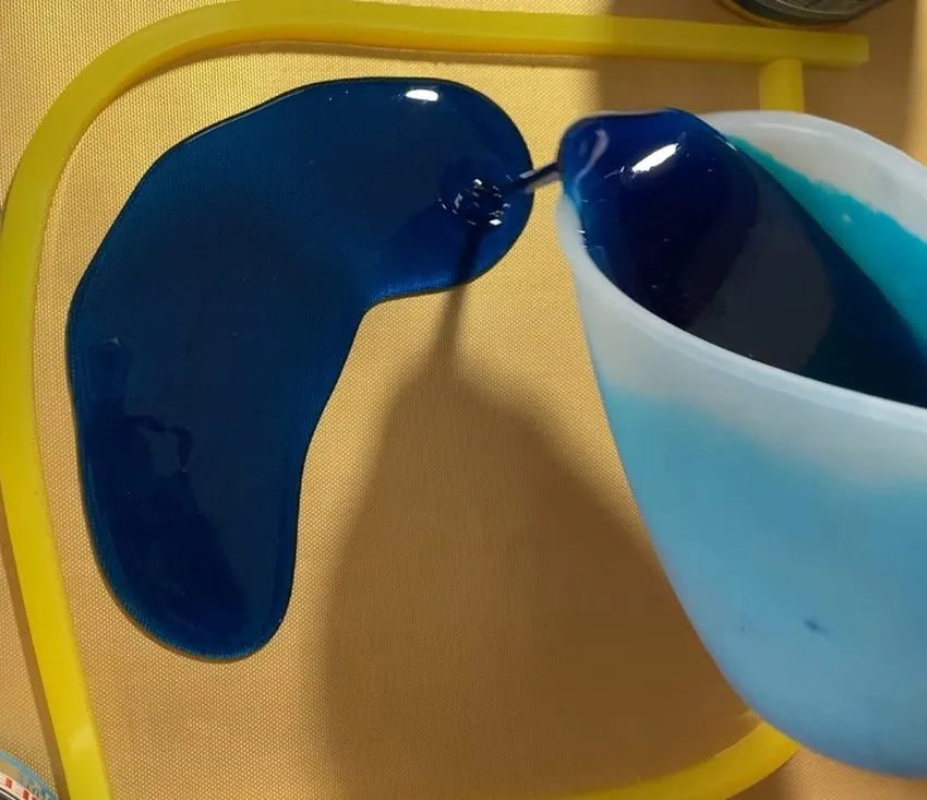 Dark blue isomalt being poured onto a surface in a puddle.