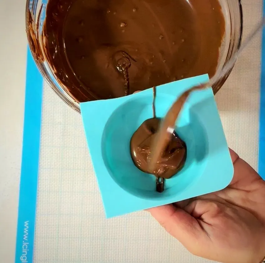 Pouring melted chocolate into a silicone mold.