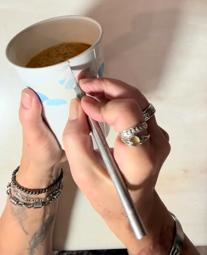 Hands use a precision knife to cut the paper cup and release the gummy beer.
