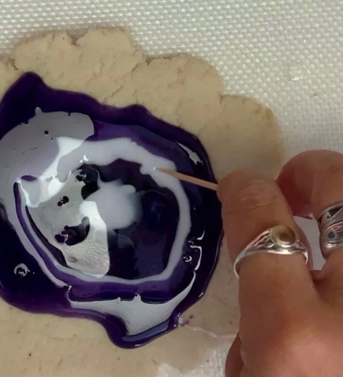 Swirling melted isomalt on a sugar cookie to create geode rings.
