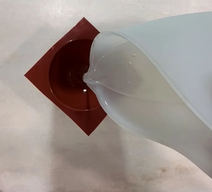 Clear isomalt being poured into a half-sphere silicone mold.