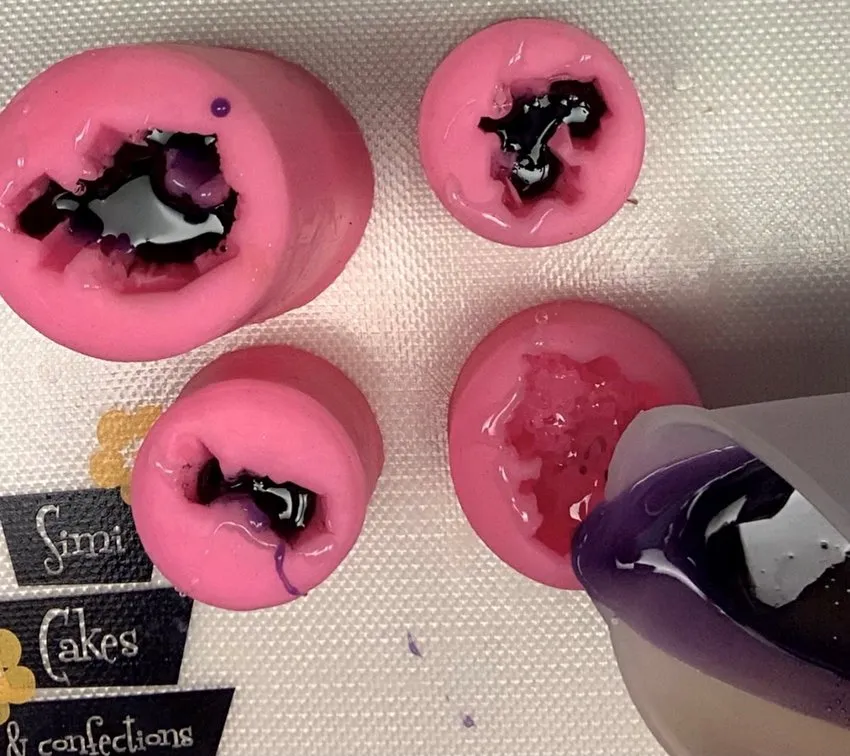 Pouring purple melted isomalt into gemstone silicone molds.
