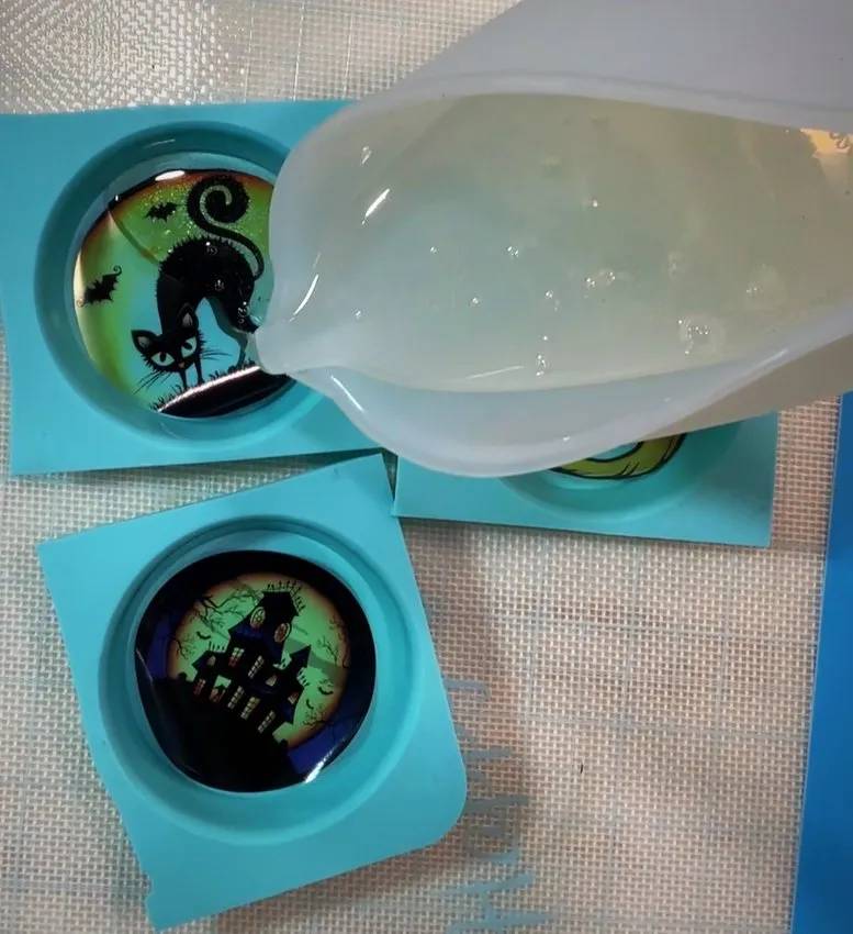 Melted isomalt is poured from a cup into silicone lollipop molds.