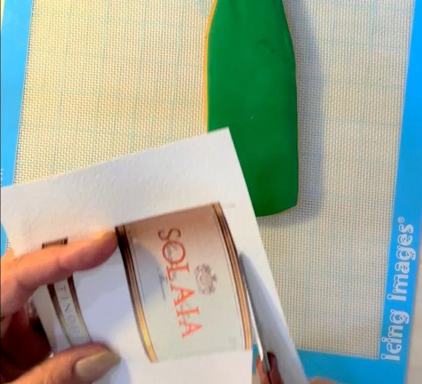 Hand holding a printed edible wafer paper wine label over a green cookie.