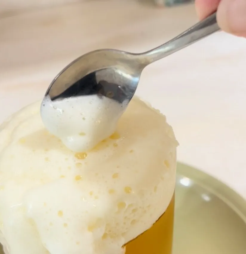 A spoon adds white gelatin foam dripping down the side of the gummy pint.