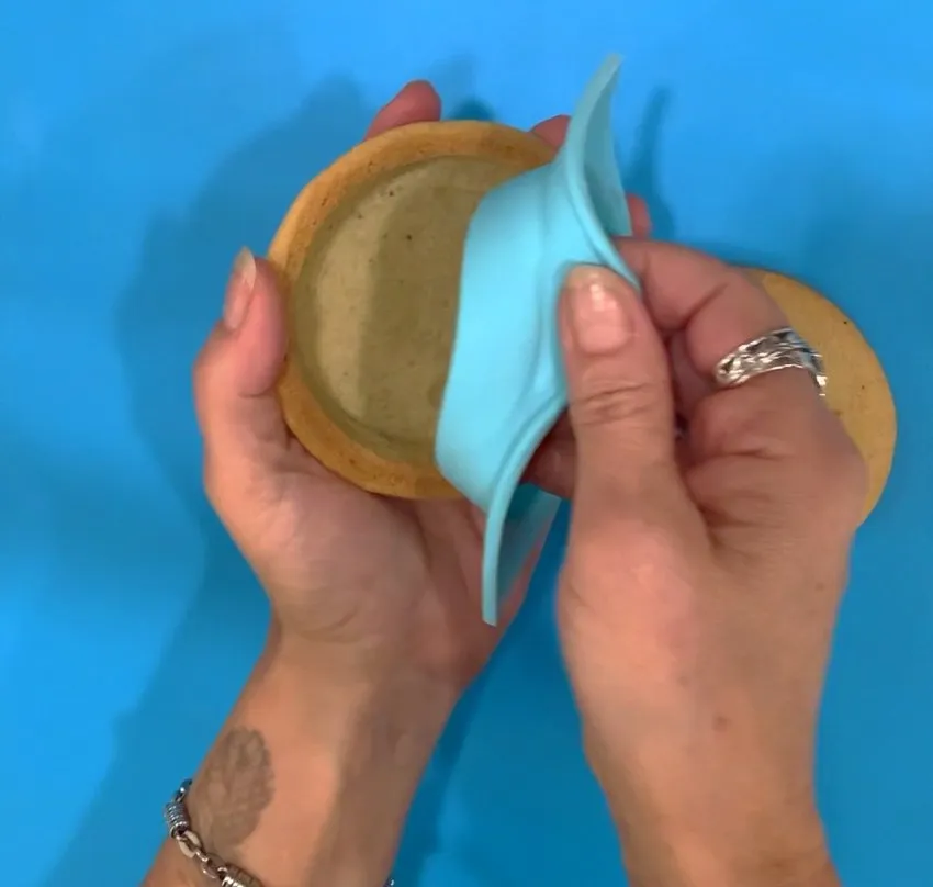 Removing the silicone mold from a baked cookie.