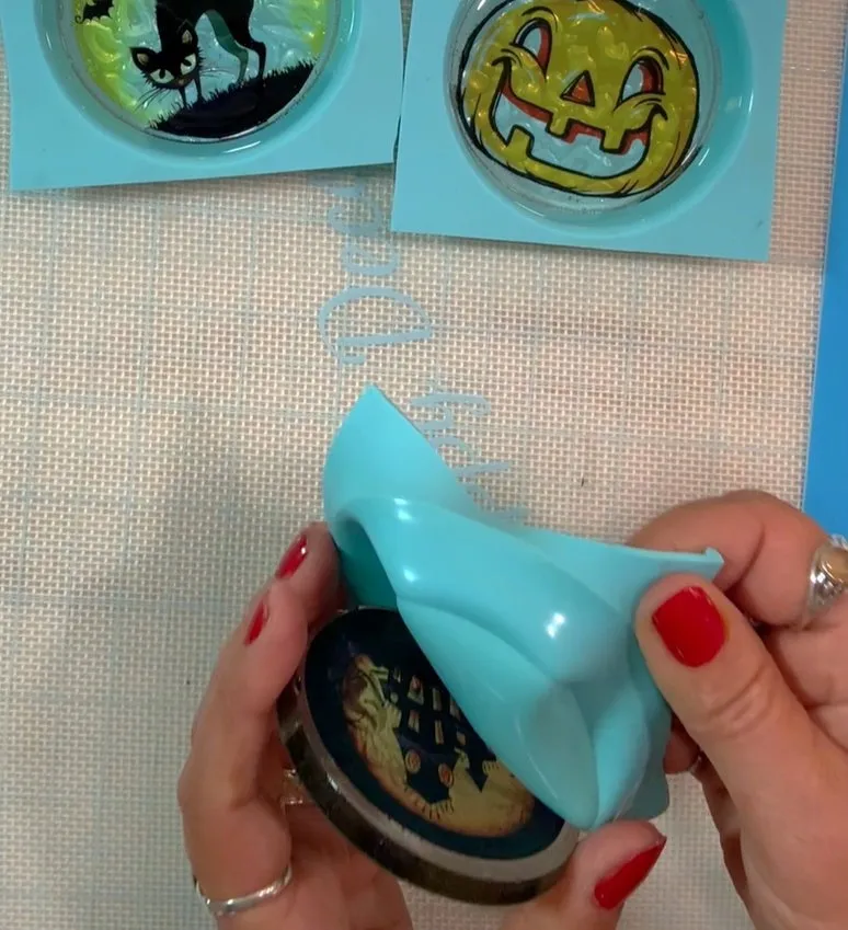 Hands peel finished isomalt lollipops out of blue silicone molds.