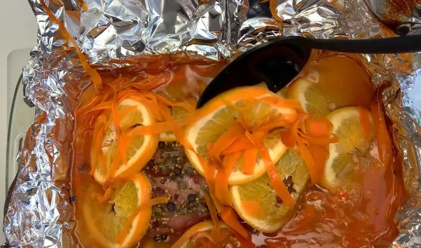 Cooked brisket with orange slices and spices in the pan