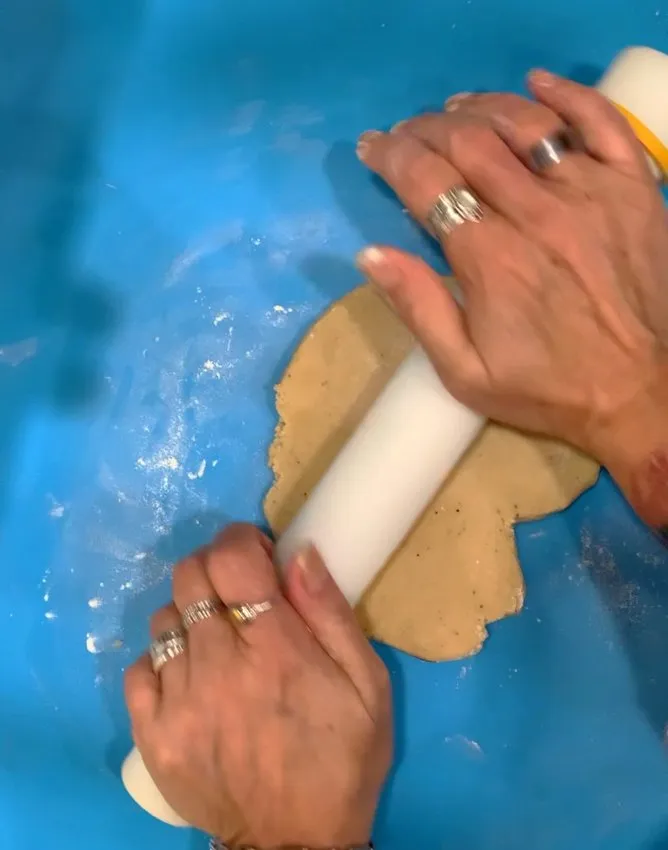 Rolling out sugar cookie dough with a rolling pin.