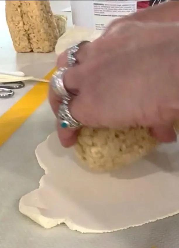Hand pressing the rice-cereal body onto rolled white fondant.