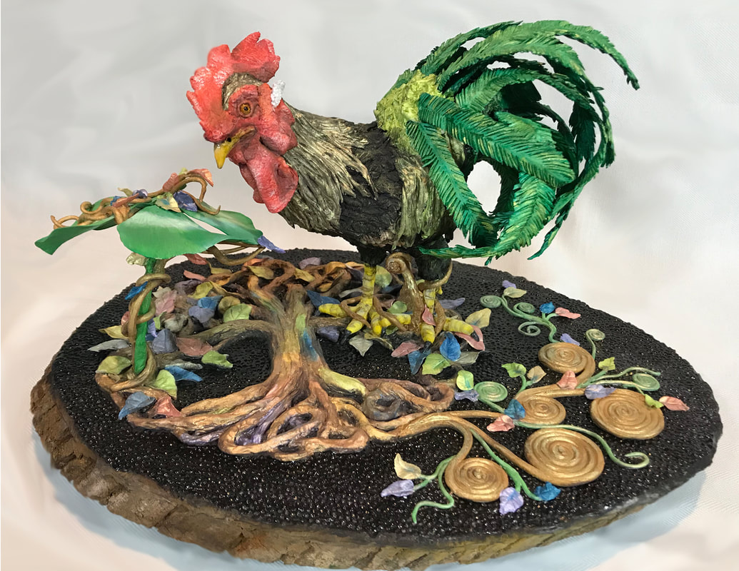 A detailed quilling art sculpture of a rooster with a red comb and green tail feathers stands atop a base of intricate, colorful paper vines and leaves.
