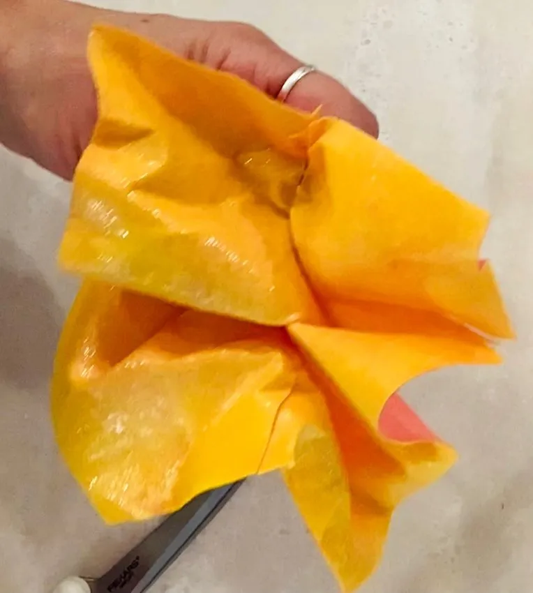 Hand holding crumpled wet wafer paper with a knife visible in background.