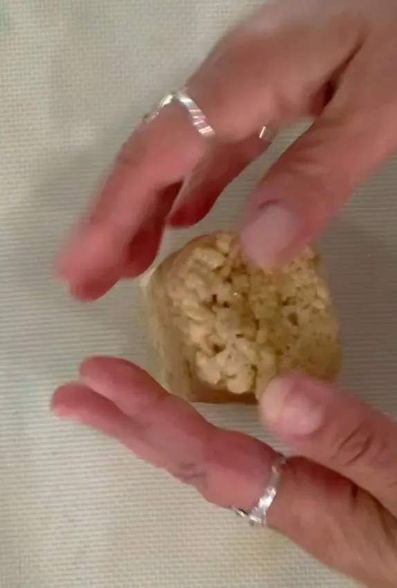 Hands shaping a rice-cereal treat into a bunny body shape.