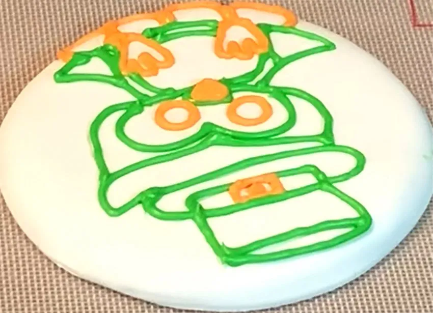 Cookie with owl outline icing set aside to dry.