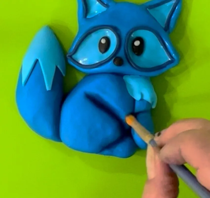 Hand brushing edible petal dust onto the fondant fox for shadowing.