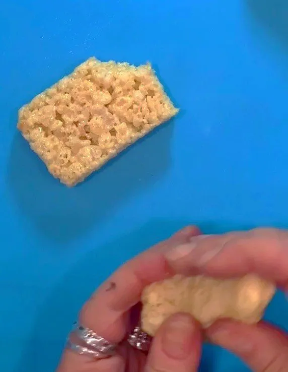 A hand shapes a Rice Krispie treat into the gnome body form.