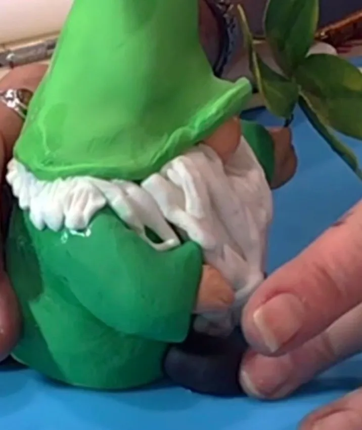 Hands attach black fondant boots to the bottom of the gnome.
