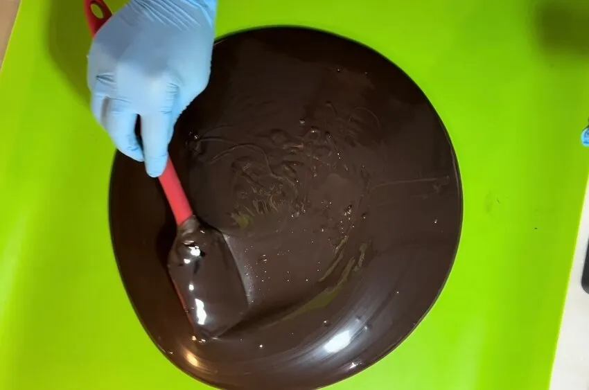 Spreading melted chocolate into a brim shape on a silicone mat